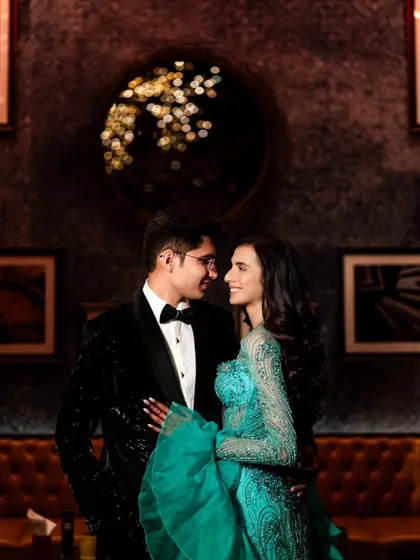 A classic cocktail party portrait with a touch of glamour. The couple's gaze towards each other speaks of their deep connection, set against a moody, elegant backdrop.