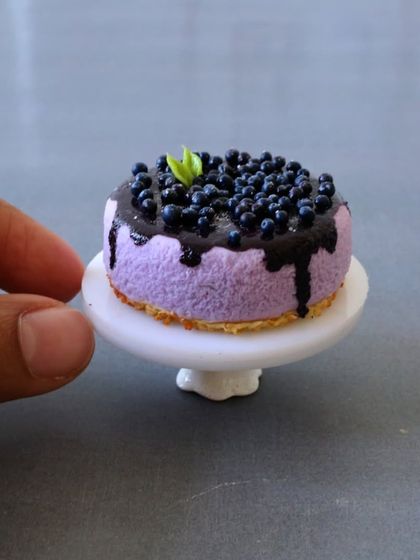 A close-up of my miniature blueberry cheesecake, complete with a glossy topping and tiny mint leaf.
