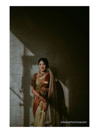 A classic bridal portrait using light and shadow. The bride stands in a sliver of light, creating a dramatic and elegant image that highlights her features and attire.