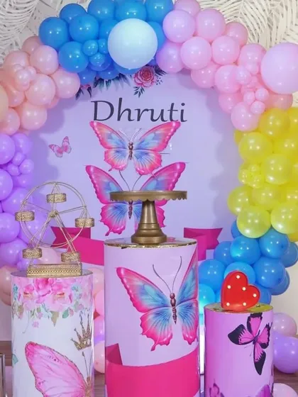 A close-up of the butterfly theme, showing the custom printed backdrop and pedestals. The mix of pastel balloons in different colors creates a very cheerful and lively look.