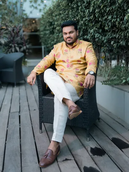 The groom looking relaxed and happy in a vibrant yellow kurta, seated outdoors before the festivities begin.