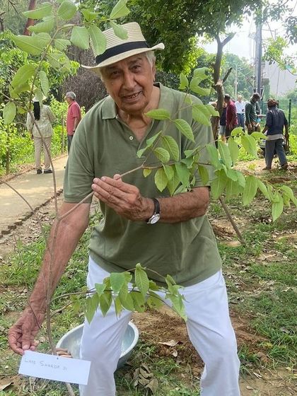 A senior citizen holds up a native sapling, ready to plant it and continue the legacy of greening Gurgaon for future generations.
