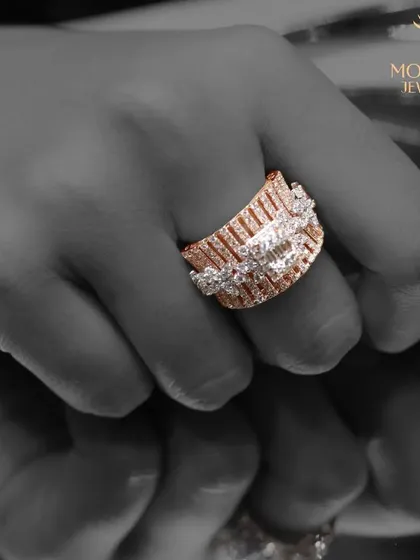 A powerful image of a wide, architectural diamond ring in rose gold, presented in a high-contrast black and white style.