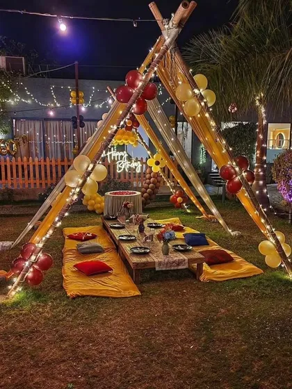 A classic teepee-style gazebo setup on a lawn, decorated with balloons and fairy lights, ready for a memorable outdoor birthday party.