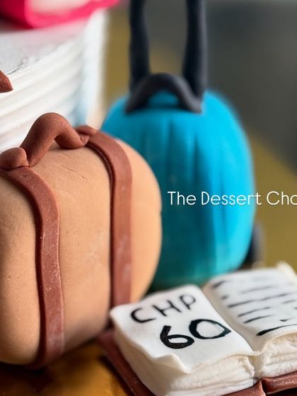 The tiny, detailed fondant luggage and book, representing a love for travel and reading.