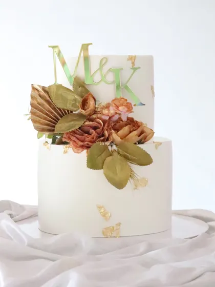 Capturing that perfect boho vibe with this two-tier engagement cake. The design uses earthy tones, dried palm spears, and muted florals, finished with a custom initial topper for a personal touch.