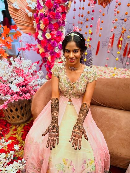 The bride looks stunning against the floral decor, her hands open to display the intricate portrait mehndi.