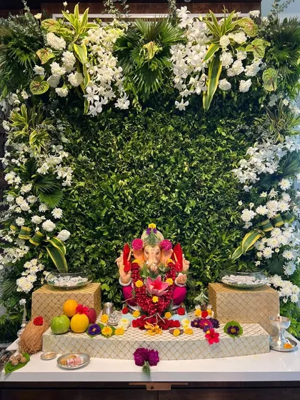 This modern and elegant Ganpati backdrop features a dense wall of fresh greenery, accented with clusters of white orchids and other exotic white flowers. It’s a perfect example of how we blend contemporary style with traditional reverence.