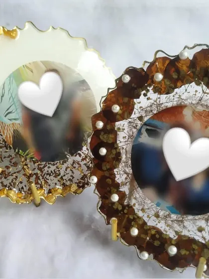This pair of photo frames was created using preserved rose petals. One frame features a clean white background with gold flakes, while the other uses the natural look of the petals, showing the versatility of the design.