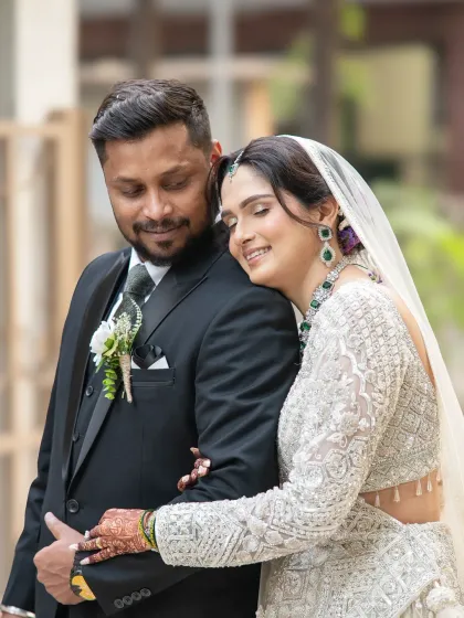 A quiet moment of connection. The bride rests her head on the groom's chest, a simple gesture that speaks volumes about their comfort and love for each other.