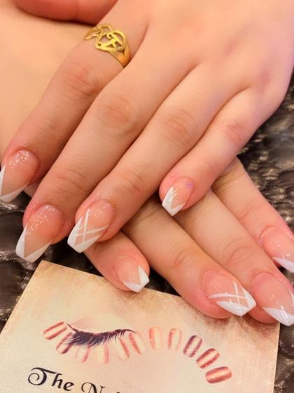 A modern and clean design on square nails. This set features a white French tip with additional white geometric lines for an abstract look.