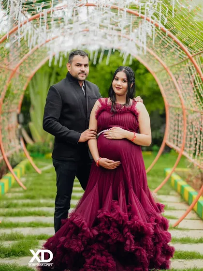 A stunning portrait of a couple inside a tunnel of lights, with the mother-to-be in a deep maroon gown.