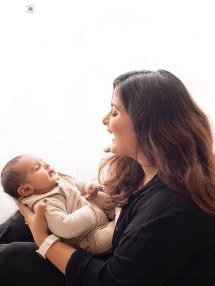 A mother's joyful smile as she plays with her new baby. This photo is full of light and happiness, capturing a real, unposed moment of connection.