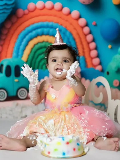 Hands up if you love cake! This is the aftermath of a very successful cake smash. The colorful backdrop makes the photo pop.