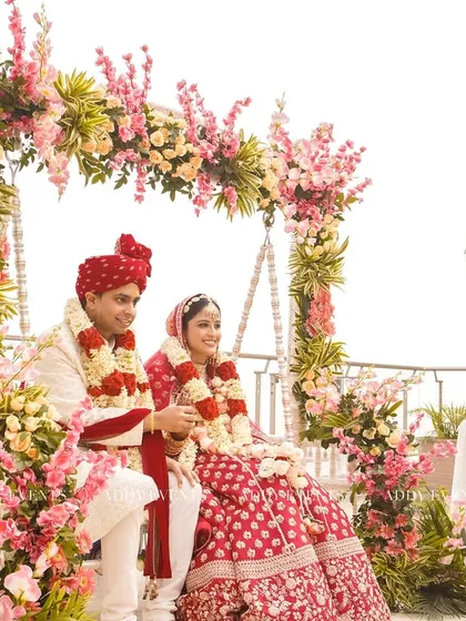 A perfect moment for a rooftop wedding. The couple is framed by a beautiful floral swing, combining blush pink blooms with the open sky for a serene and romantic ceremony.