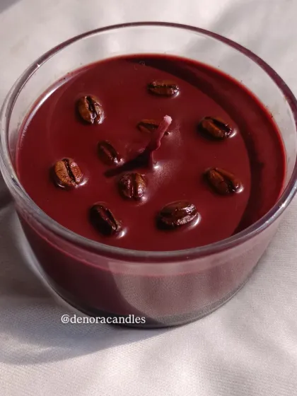 A dark, rich coffee-scented candle in a glass jar, topped with real coffee beans for an authentic look and aroma.