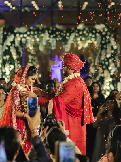 A joyous varmala moment in the midst of family and friends, with a shower of red petals. We ensure the celebration feels inclusive and captures the energy of your loved ones.
