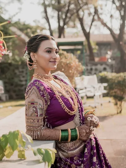A candid shot of the bride, her smile bright and genuine. The natural lighting highlights her flawless skin and the rich embroidery of her blouse.