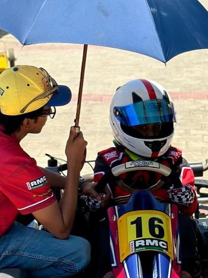 A coach giving advice to a young driver under an umbrella.