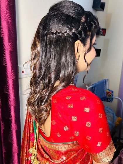 A modern half-up, half-down hairstyle with a braided crown and soft curls.