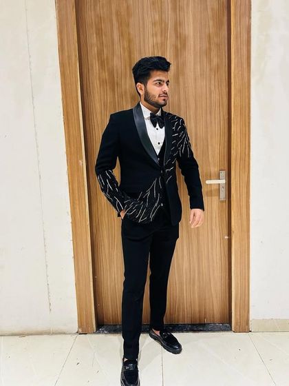 A client in a modern black three-piece suit. The jacket features asymmetrical silver embroidery, adding a contemporary artistic touch.