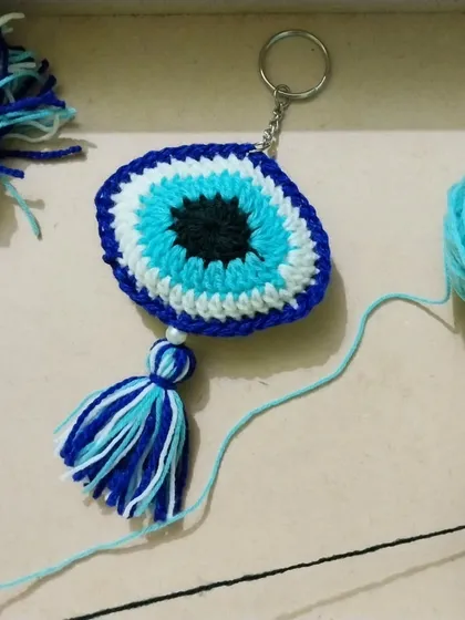 The evil eye keychain in the making, surrounded by the yarn I use to create it.