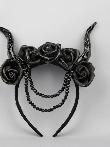 A gothic-style Halloween headband with black horns, roses, and beaded chains.
