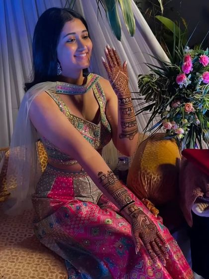 A candid shot of a happy bride, her arms adorned with our detailed henna work, adding to the festive atmosphere of her mehandi ceremony.