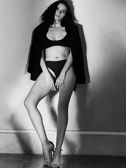 A black and white shot that highlights the power of shadow and light. The subtle makeup and naturally textured hair create a timeless and moody atmosphere, perfect for an artistic portfolio or a minimalist editorial.