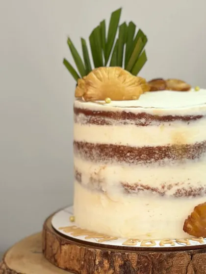 A close-up of the semi-naked pineapple cake, showing the texture of the sponge and the delicate buttercream.