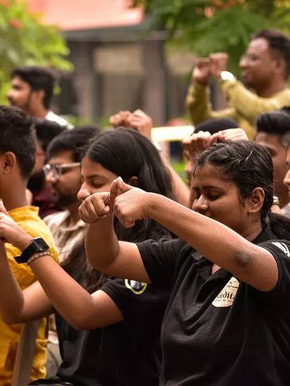 A group of participants fully engaged in learning sign language, their hands moving in unison. This image captures the collective effort and focus of our workshops.