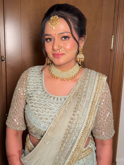 A portrait of the bride in her pastel lehenga. The makeup is soft and romantic, with a focus on creating a flawless, glowing complexion.