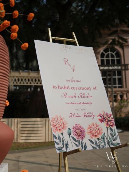 The elegant welcome sign for the groom's Haldi ceremony, featuring a floral watercolor design and a simple, clean font.