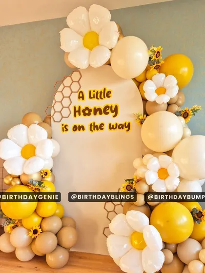 A sweet "A Little Honey is on the way" baby shower theme, with a honeycomb backdrop, daisy-shaped balloons, and a warm yellow and beige color scheme.