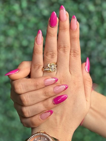Pretty in pink! This vibrant pink design features a modern French tip style with glitter details for a fun and feminine look.