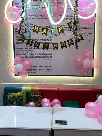 A closer look at the cafe birthday decor, showing the placement of balloon clusters around the main seating area to add a festive touch without overwhelming the space.