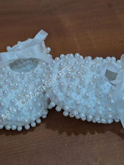 A side view of the pearl booties, showing how the pearls are woven into the crochet stitches for a secure and beautiful finish.