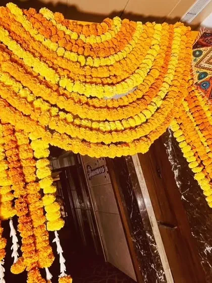 A close-up of the dense marigold garlands used to create a stunning traditional entryway. The vibrant orange and yellow hues are symbolic of celebration in Indian culture.