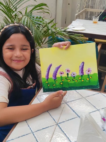 A young guest happily presents her unique floral painting, a wonderful keepsake from a fun birthday celebration.