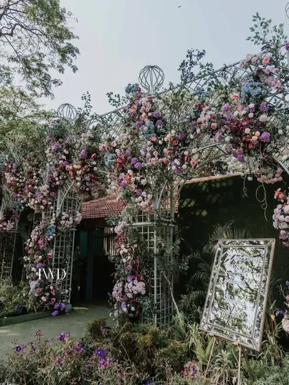The entrance to the vintage garden wedding, featuring elaborate floral arrangements on wrought iron structures. This sets a tone of classic romance from the very first step.