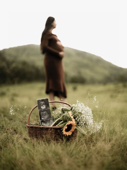 An artistic shot with the focus on the basket of flowers and sonogram pictures in the foreground, while the mom-to-be stands thoughtfully in the blurred background.