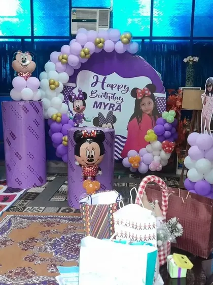 A complete Minnie Mouse themed birthday setup for Myra. We transformed this home space with a personalized backdrop, character cutouts, and purple and white balloon pillars, creating a magical party zone.