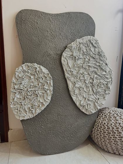 The full view of the grey sculptural piece. The organic shape of the board itself adds to the artwork's unique character, making it feel like a natural formation.