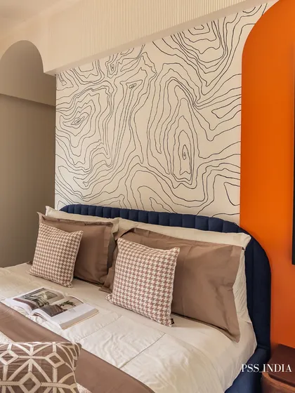A bold and artistic approach to a feature wall. The topographic line art behind the bed, paired with a vibrant orange accent wall, creates a dynamic and personalized space that is full of energy.