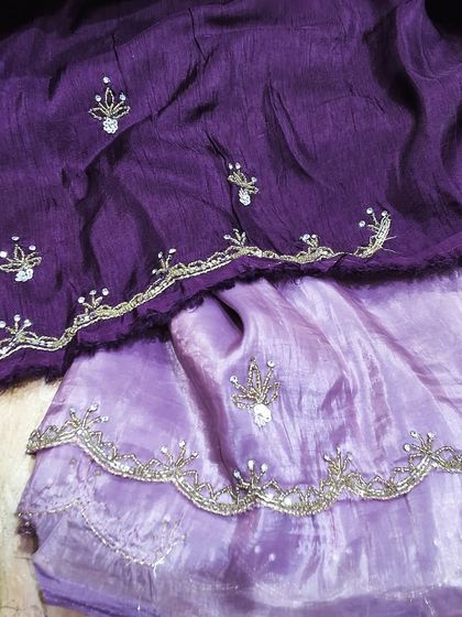 A lovely crush tissue saree in a dual-tone purple shade. The fabric has a beautiful texture and is adorned with delicate self-colored embroidery and a scalloped border.