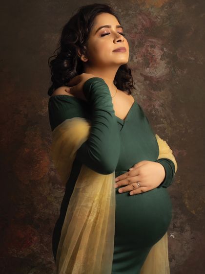 Embracing the bump with a look of serene contentment. This close-up in the green gown is full of warmth and emotion.