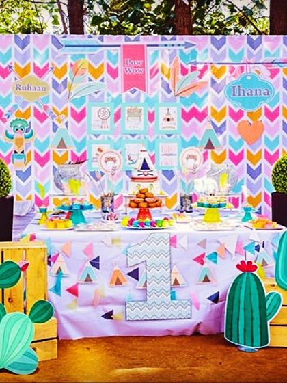 A vibrant Aztec and tribal-themed dessert table for a twins' first birthday. The colorful geometric backdrop and cactus cutouts created a playful and modern look.