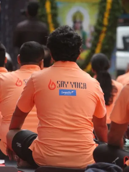 A view from behind of our students during a seated meditation at the International Yoga Day event. The matching orange shirts with the SAY Yoga logo reinforce our identity as a unified tribe.