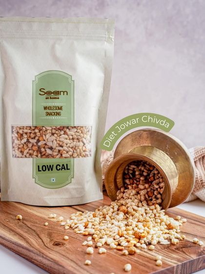 My Diet Jowar Chivda spills from a brass cup onto a wooden board. This light, low-calorie snack is a great choice for anyone looking to snack better.