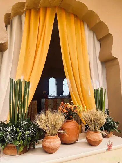 An entryway vignette for the Haldi, featuring terracotta pots with wheat stalks and baby's breath, creating a warm and rustic welcome.